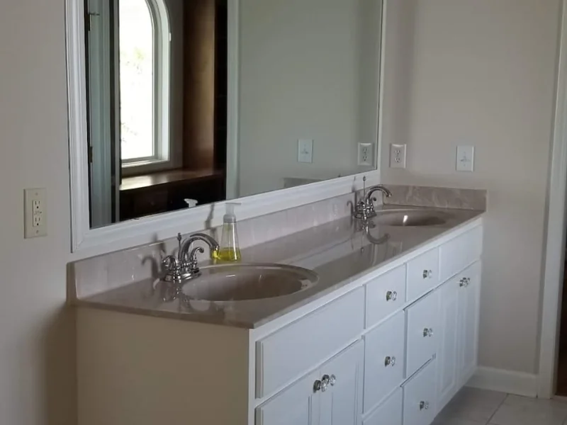 Bathroom with a white vanity, mirror and light wall finish
